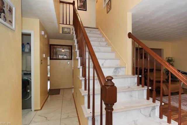 staircase featuring washer / dryer, baseboards, and marble finish floor