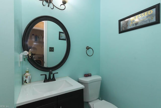 half bathroom with vanity, washer / dryer, and toilet