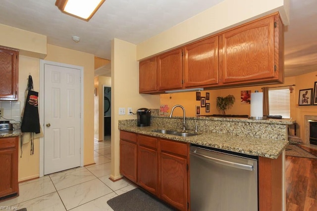 kitchen with light stone counters, brown cabinets, stainless steel dishwasher, marble finish floor, and a sink