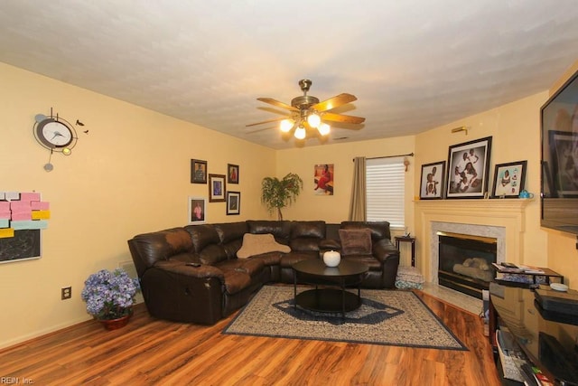 living room featuring a ceiling fan, wood finished floors, and a premium fireplace