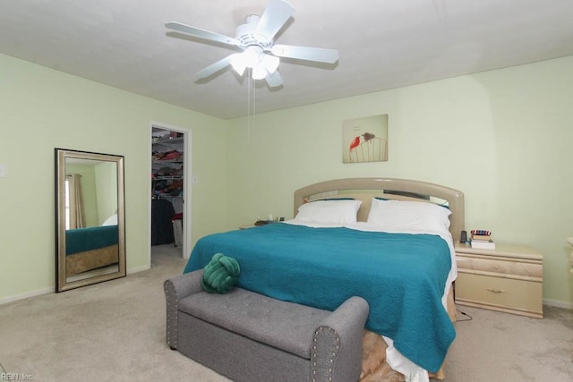 carpeted bedroom featuring a walk in closet, baseboards, a closet, and a ceiling fan