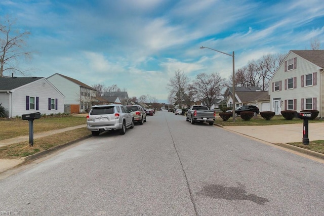 view of road featuring sidewalks, a residential view, curbs, and street lights