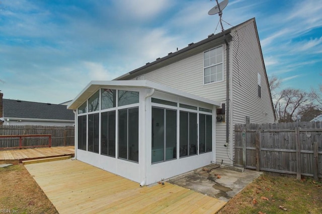 view of side of property with a fenced backyard, a deck, and a sunroom