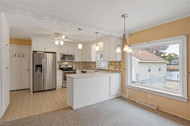 kitchen featuring visible vents, a peninsula, plenty of natural light, a sink, and appliances with stainless steel finishes