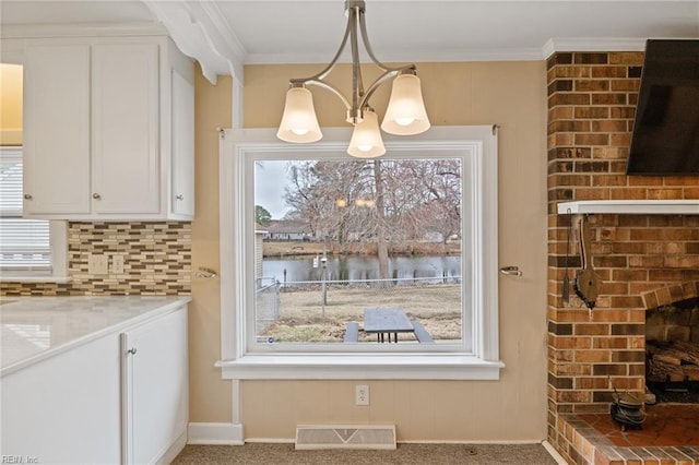 kitchen featuring visible vents, a water view, backsplash, and ornamental molding