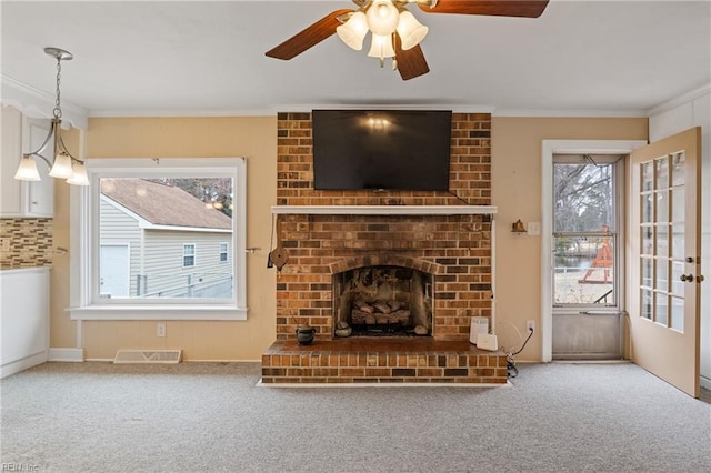 unfurnished living room with visible vents, carpet flooring, crown molding, and a ceiling fan