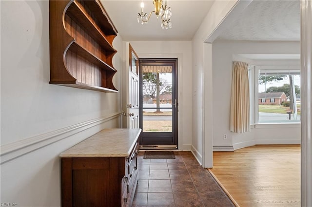 entrance foyer featuring baseboards, a baseboard radiator, a wealth of natural light, and a chandelier