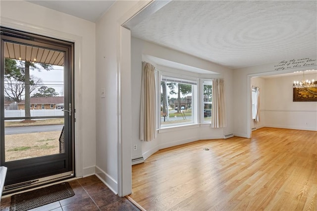 entrance foyer featuring an inviting chandelier, wood finished floors, baseboards, and a textured ceiling