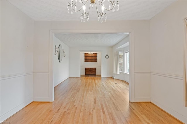 interior space featuring a notable chandelier, light wood-type flooring, and baseboards