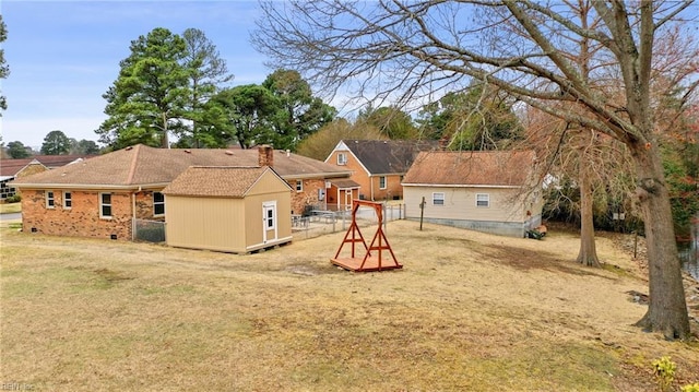 back of house with an outbuilding, fence, a yard, a chimney, and a storage shed