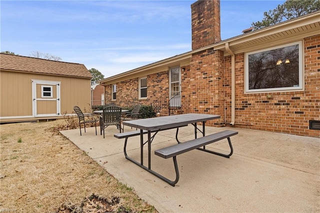 view of patio / terrace featuring outdoor dining space and an outbuilding