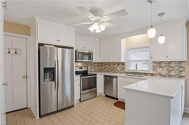 kitchen with light countertops, a peninsula, white cabinets, stainless steel appliances, and a sink