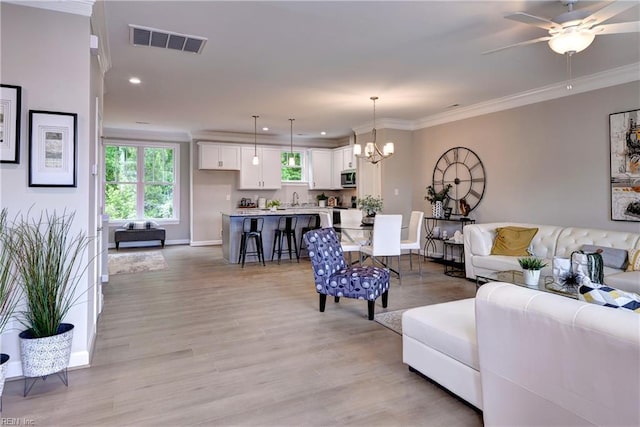 5311 Salzman St, Williamsburg, VA 23188 - living room featuring a chandelier, baseboards, light wood-style floors, plenty of natural light, and ornamental molding