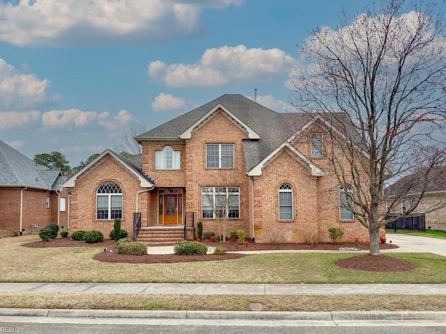 traditional home with a front lawn, brick siding, and a shingled roof