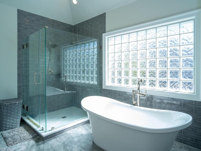 full bath with a soaking tub, tile walls, and a stall shower