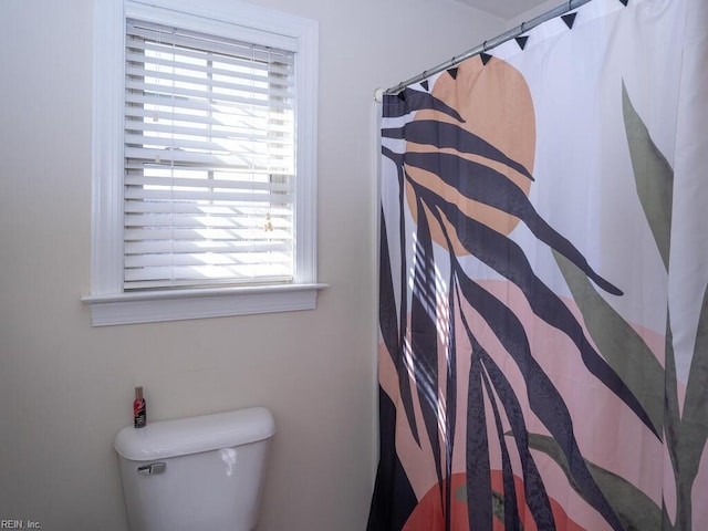 bathroom with a shower with shower curtain and toilet