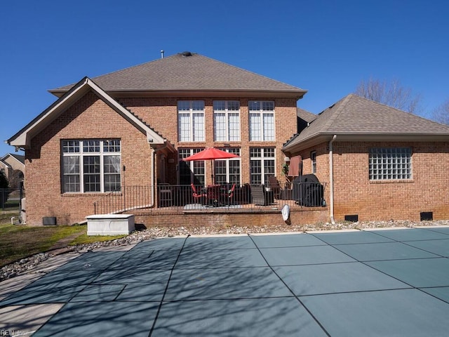 back of property featuring crawl space, a patio, brick siding, and a shingled roof