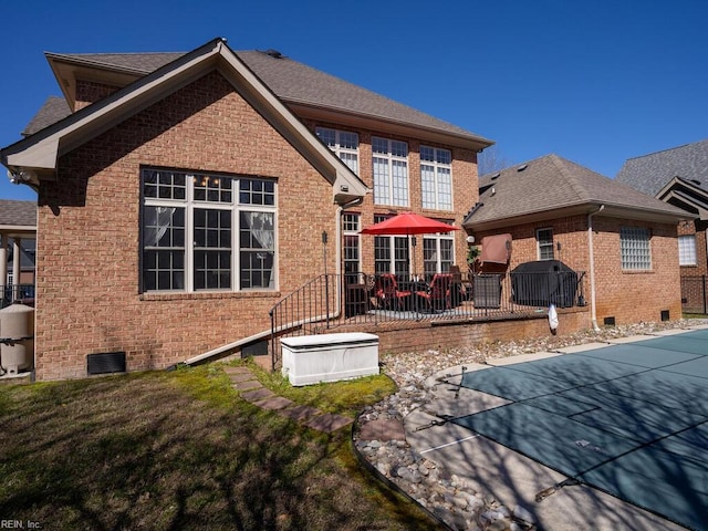 back of house featuring a yard, brick siding, roof with shingles, and crawl space