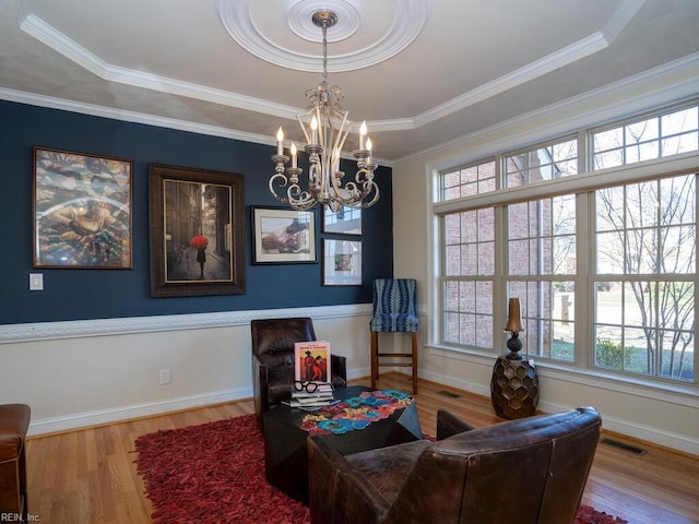 sitting room with a chandelier, visible vents, baseboards, and wood finished floors