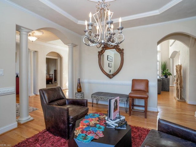 living area featuring crown molding, baseboards, an inviting chandelier, wood finished floors, and arched walkways