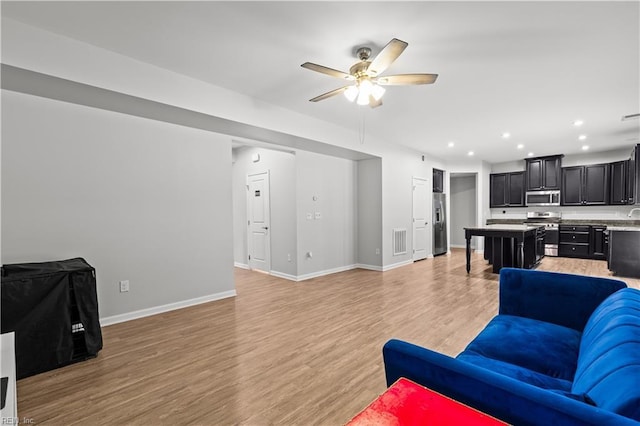 living area with light wood-type flooring, visible vents, a ceiling fan, recessed lighting, and baseboards