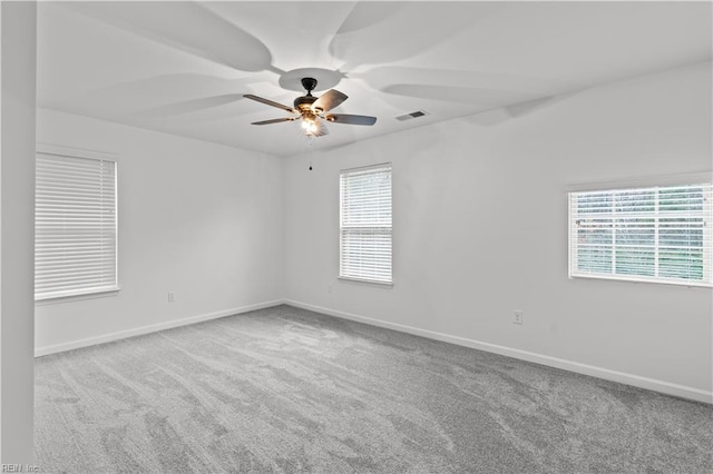 empty room featuring visible vents, carpet floors, baseboards, and ceiling fan