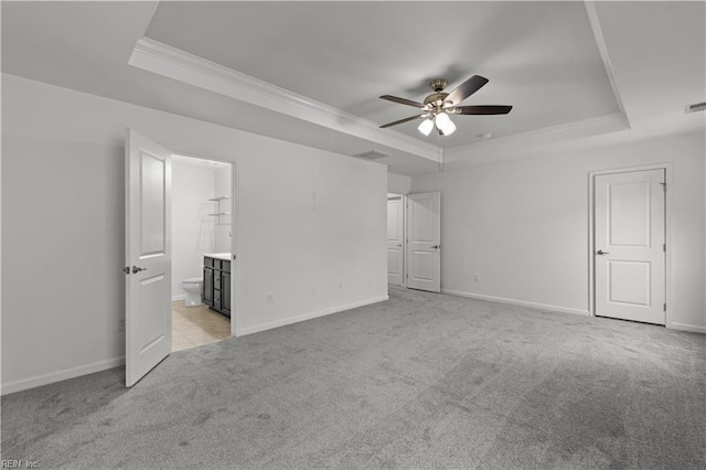 unfurnished bedroom featuring light colored carpet, a raised ceiling, baseboards, and ornamental molding