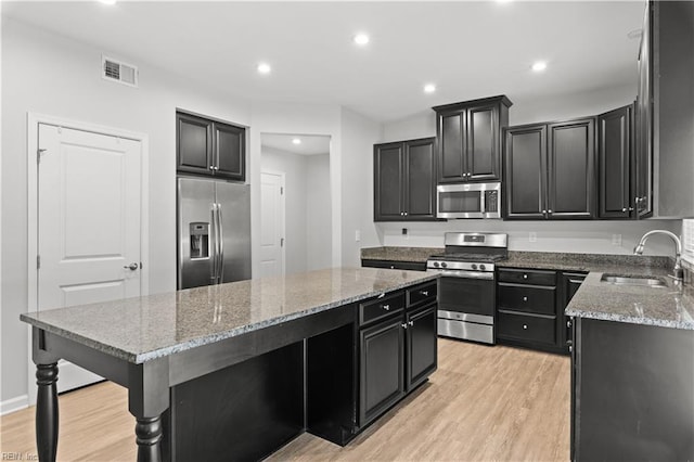 kitchen with visible vents, a sink, a kitchen island, appliances with stainless steel finishes, and dark cabinets