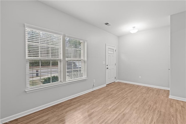 unfurnished room featuring light wood finished floors, visible vents, and baseboards