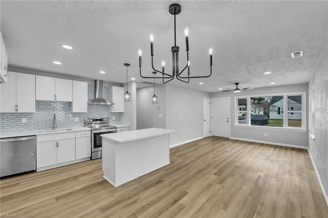 kitchen with visible vents, appliances with stainless steel finishes, light wood-style floors, wall chimney exhaust hood, and a sink