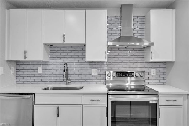 kitchen featuring a sink, appliances with stainless steel finishes, wall chimney exhaust hood, and white cabinetry