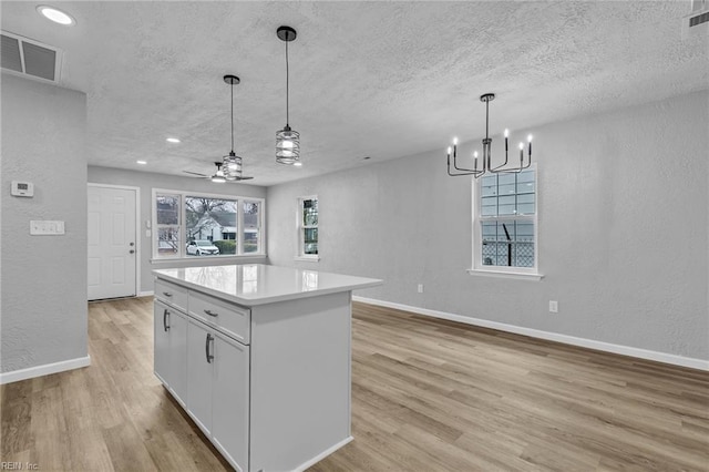 kitchen featuring light wood-style flooring, a textured wall, and a textured ceiling