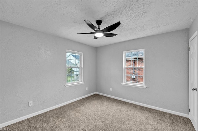 carpeted spare room featuring baseboards, a textured ceiling, ceiling fan, and a textured wall