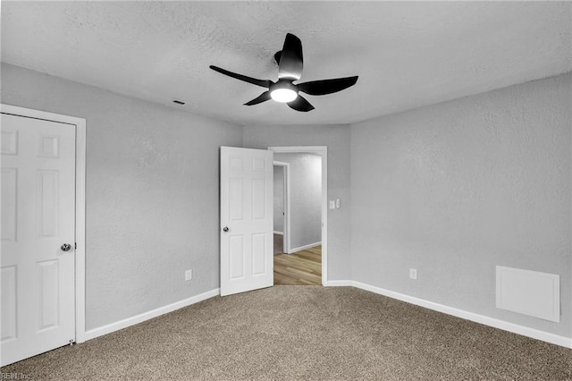 unfurnished bedroom featuring carpet, visible vents, a textured wall, and a textured ceiling