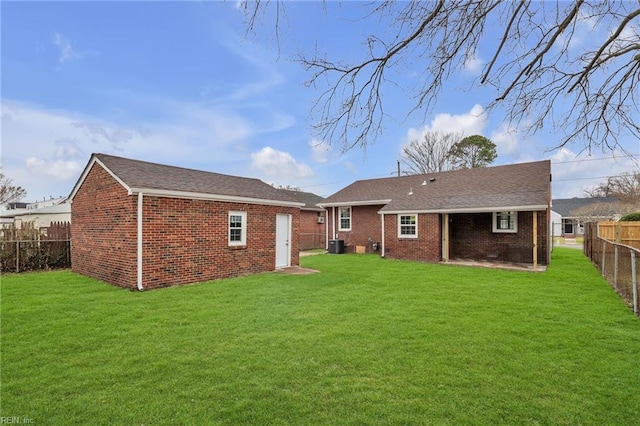 back of house featuring a yard, brick siding, and a fenced backyard