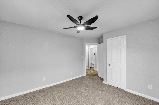 unfurnished bedroom with ceiling fan, baseboards, carpet flooring, a textured wall, and a textured ceiling