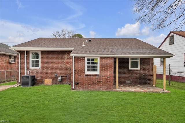 back of house with central AC unit, fence, a lawn, and brick siding