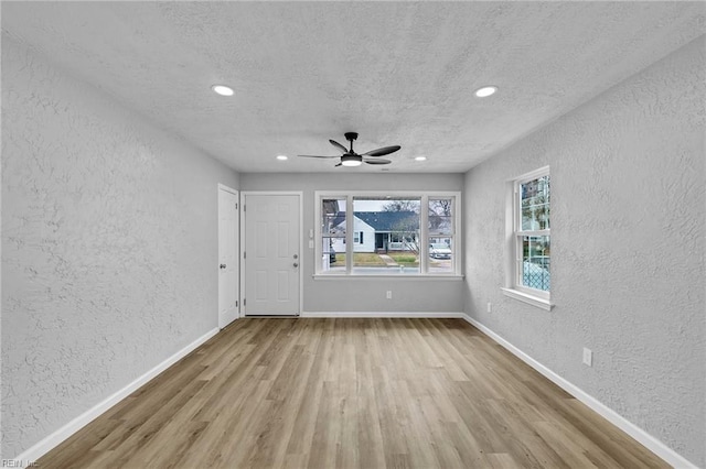 spare room featuring ceiling fan, baseboards, wood finished floors, and a textured wall