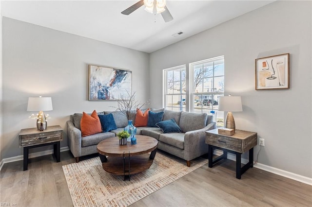 living room with baseboards, wood finished floors, visible vents, and ceiling fan