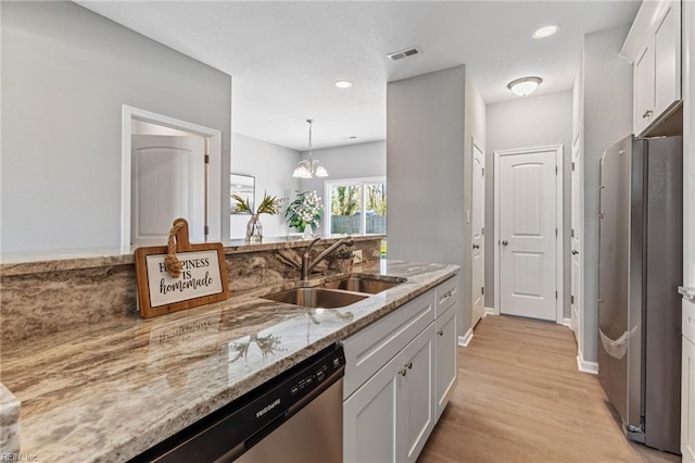 kitchen with visible vents, a sink, white cabinetry, stainless steel appliances, and light wood finished floors