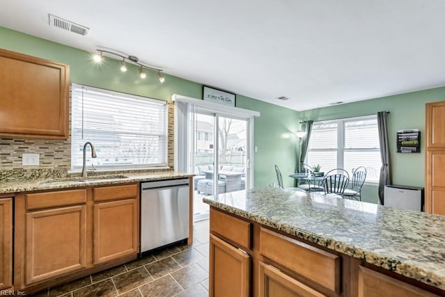 kitchen with visible vents, light stone counters, decorative backsplash, stainless steel dishwasher, and a sink