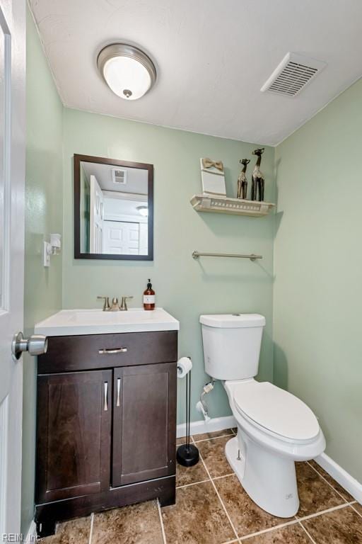 bathroom with vanity, toilet, baseboards, and visible vents