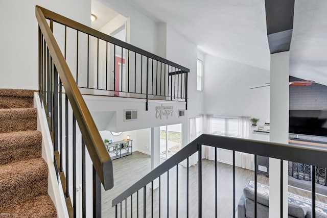 stairs with visible vents, a high ceiling, and wood finished floors