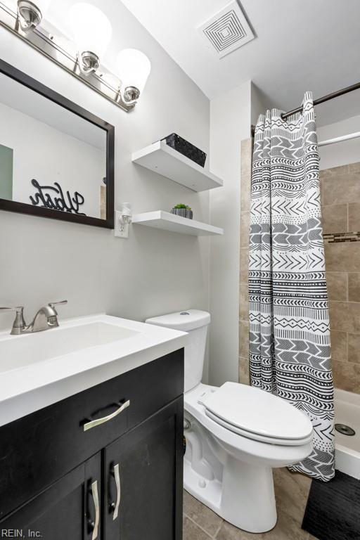 bathroom with vanity, toilet, visible vents, and a tile shower