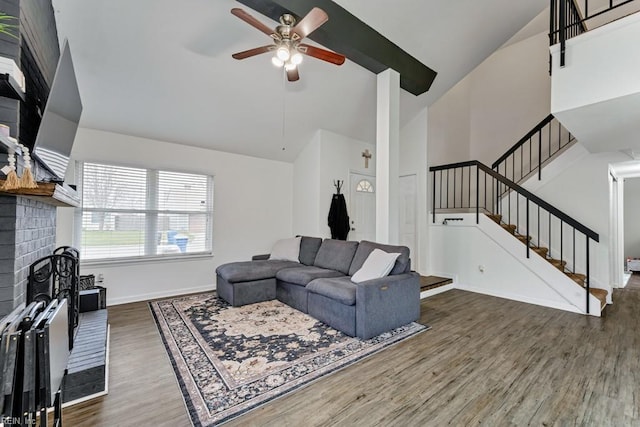 living room with ceiling fan, stairs, a fireplace, wood finished floors, and high vaulted ceiling