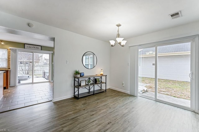 dining room featuring visible vents, wood finished floors, baseboards, and a chandelier