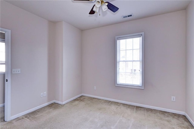 unfurnished room with visible vents, baseboards, light colored carpet, and a ceiling fan