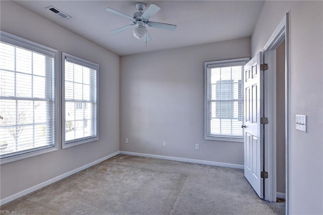 empty room featuring a ceiling fan, baseboards, visible vents, and light carpet