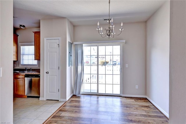 interior space with a sink, light wood-type flooring, baseboards, and a notable chandelier