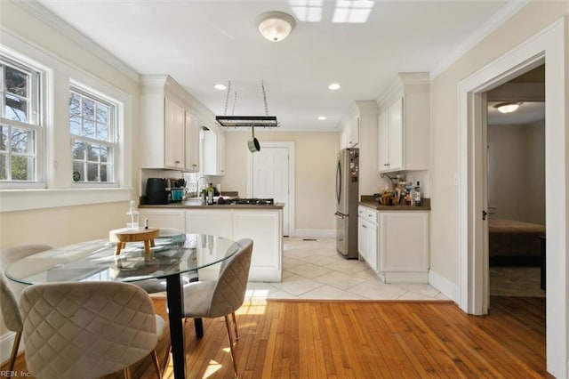 kitchen with dark countertops, white cabinets, light wood-style floors, and freestanding refrigerator